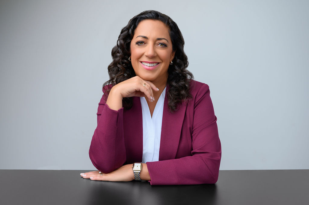 Seated professional portrait of a woman executive in a burgundy suit for a personal branding session in New Jersey